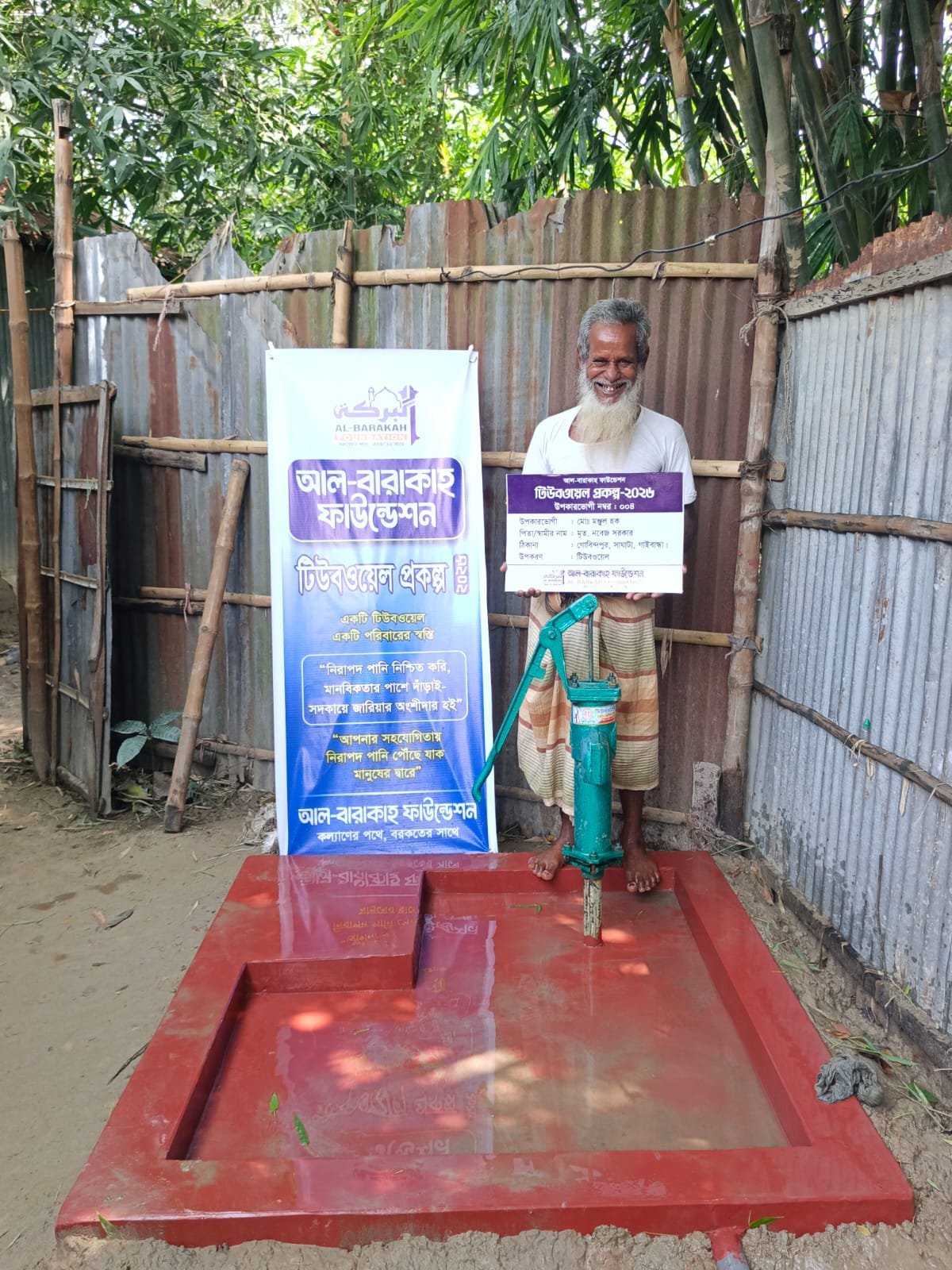 সদ্য স্থাপিত গভীর নলকূপের পাশে দাঁড়িয়ে হাসছেন উপকারভোগী